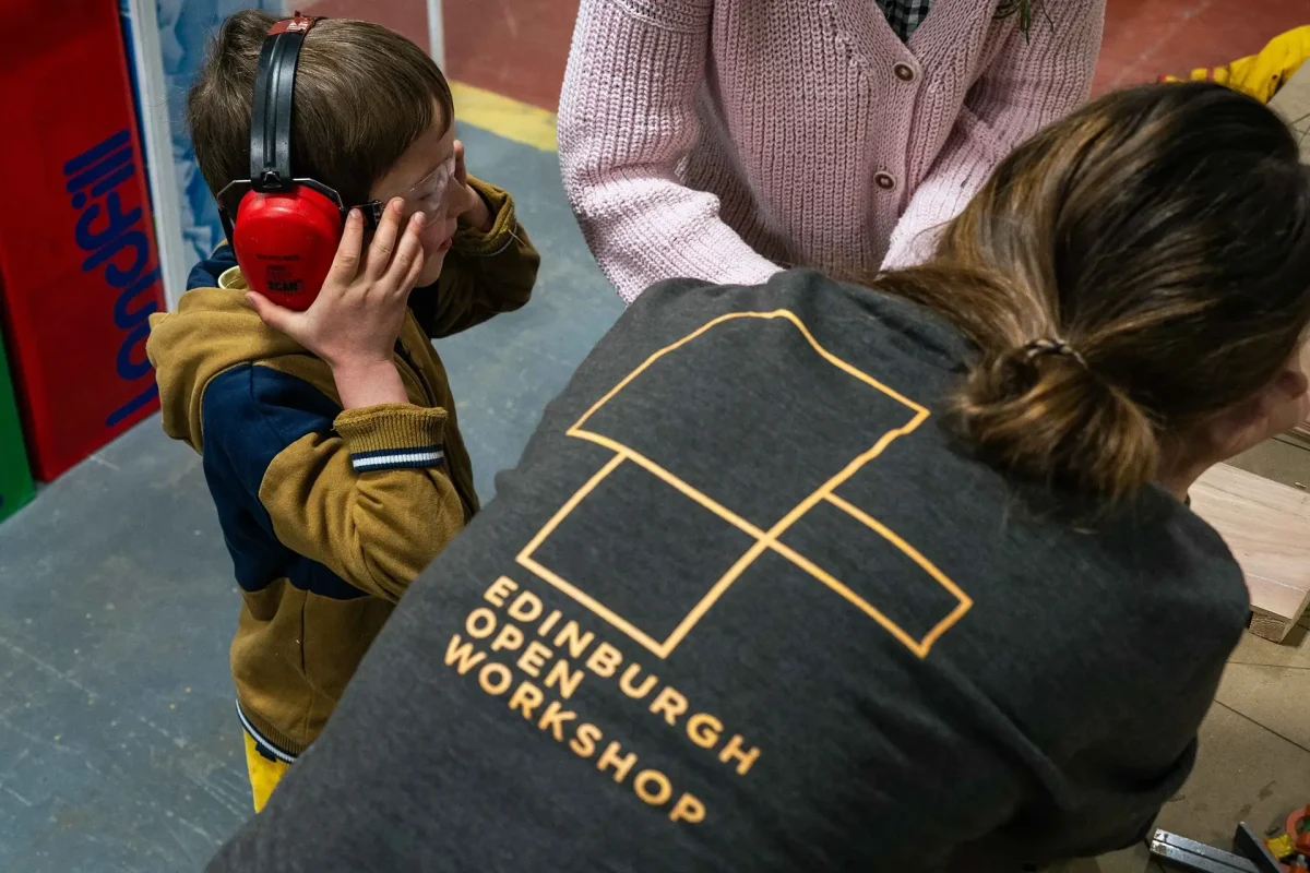 edinburgh-open-workshop-text-slider-5 Small child with noise cancelling earmuffs watches demonstration