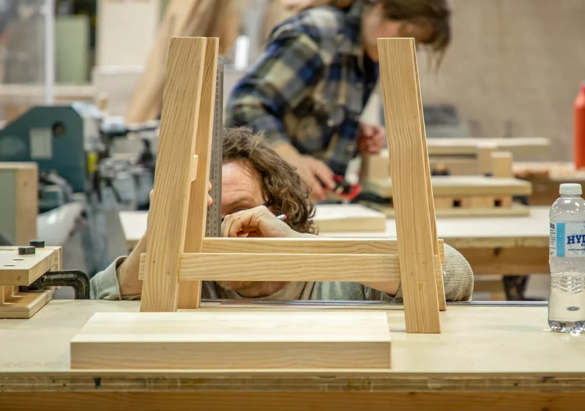 Student carefully measures out legs of wooden step stool project