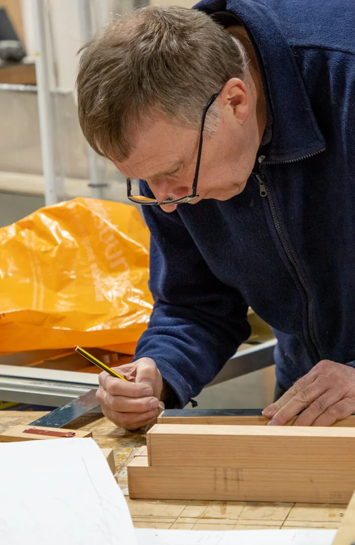 Person using pencil and ruler to mark wood for cutting